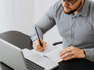 Man taking notes with laptop